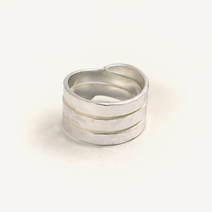 Silver ring with three horizontal bands on a light beige background