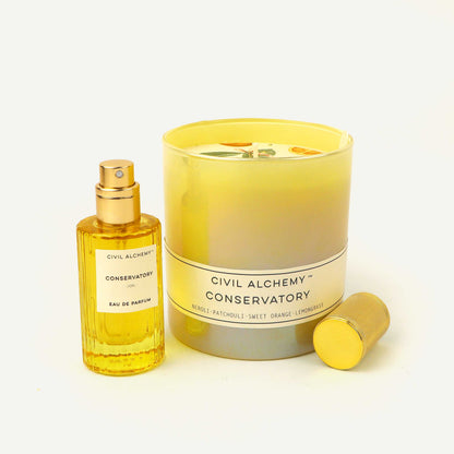 Perfume bottle and candle set with 'Civil Alchemy Conservatory' branding on a light background