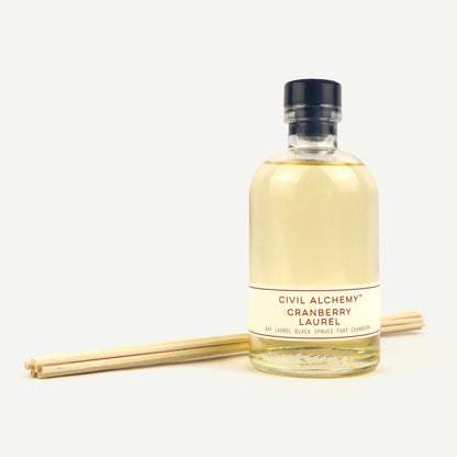 Bottle of Civil Alchemy Cranberry Laurel diffuser with reeds on a white background