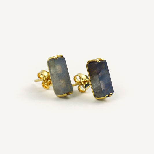 Gold earrings with blue gemstones on a white background