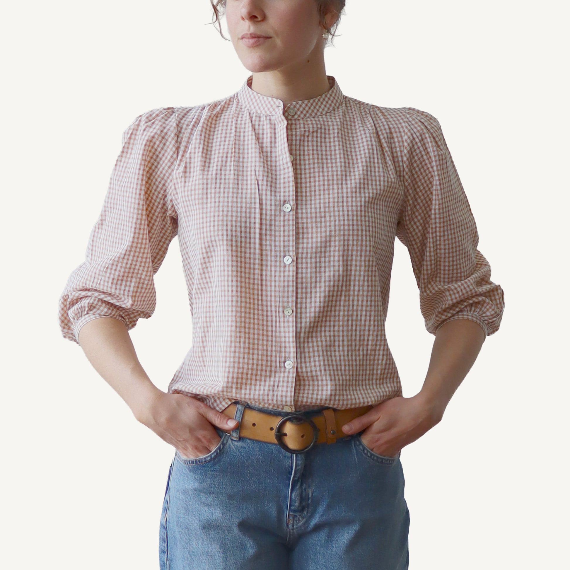 Person wearing a red and white checkered shirt with long sleeves and blue jeans on a white background