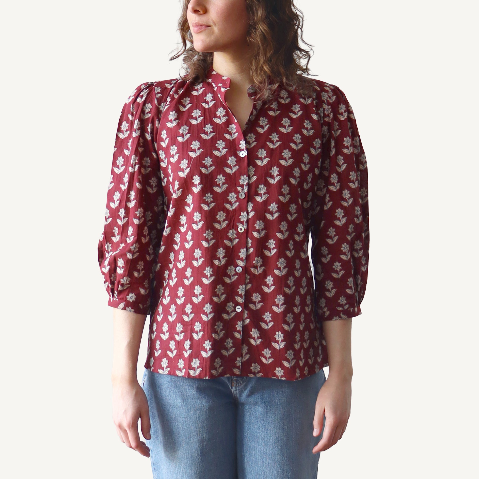 Person wearing a red floral blouse with blue jeans on a white background