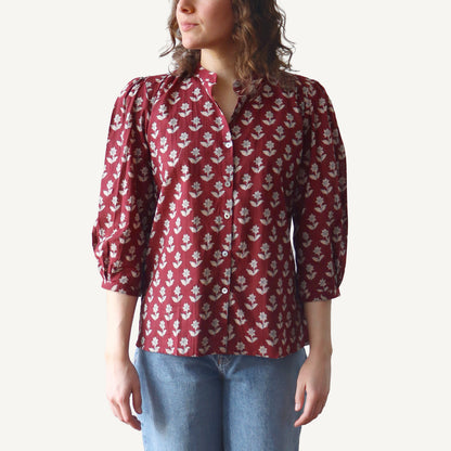 Person wearing a red floral blouse with blue jeans on a white background