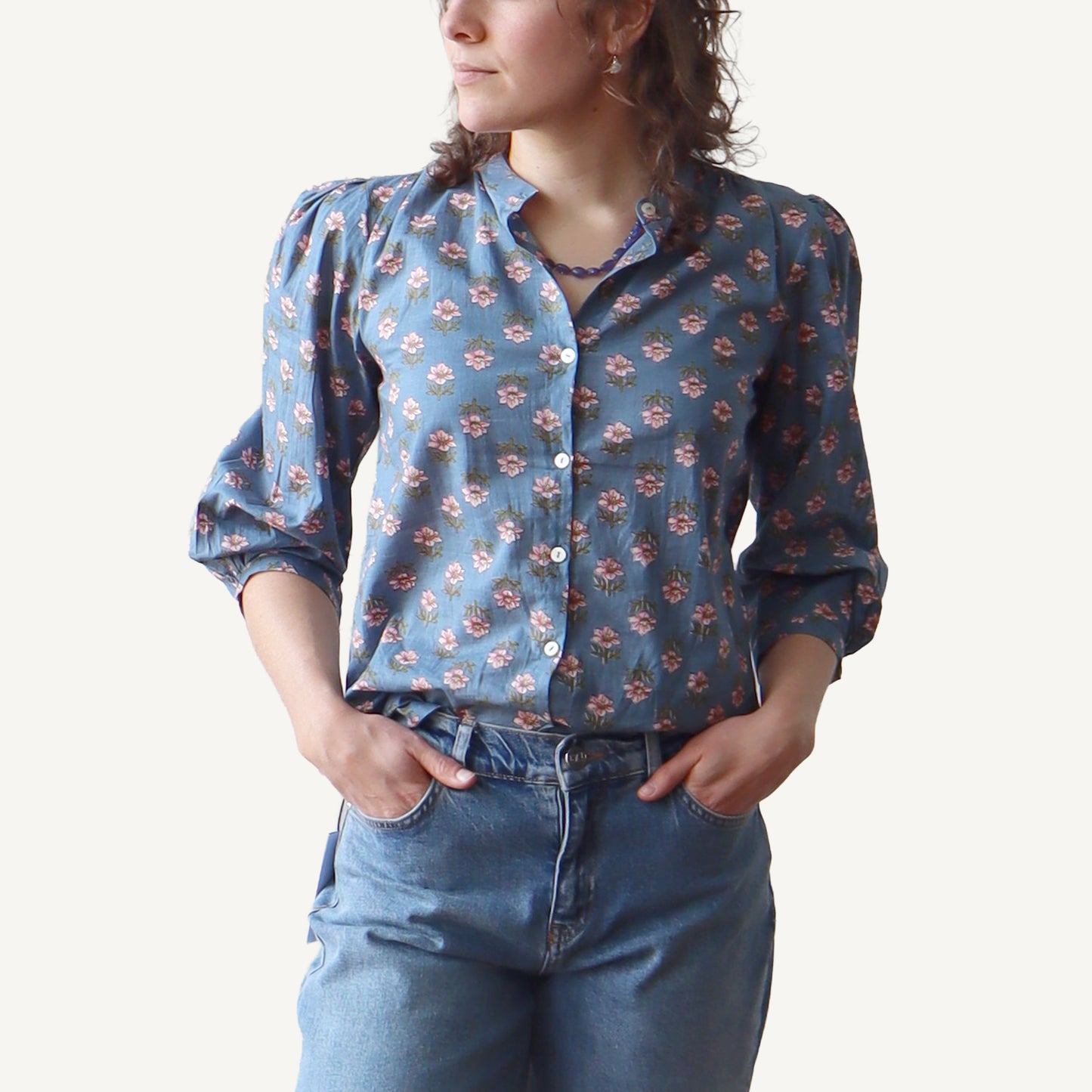 Person wearing a blue floral shirt and jeans on a white background
