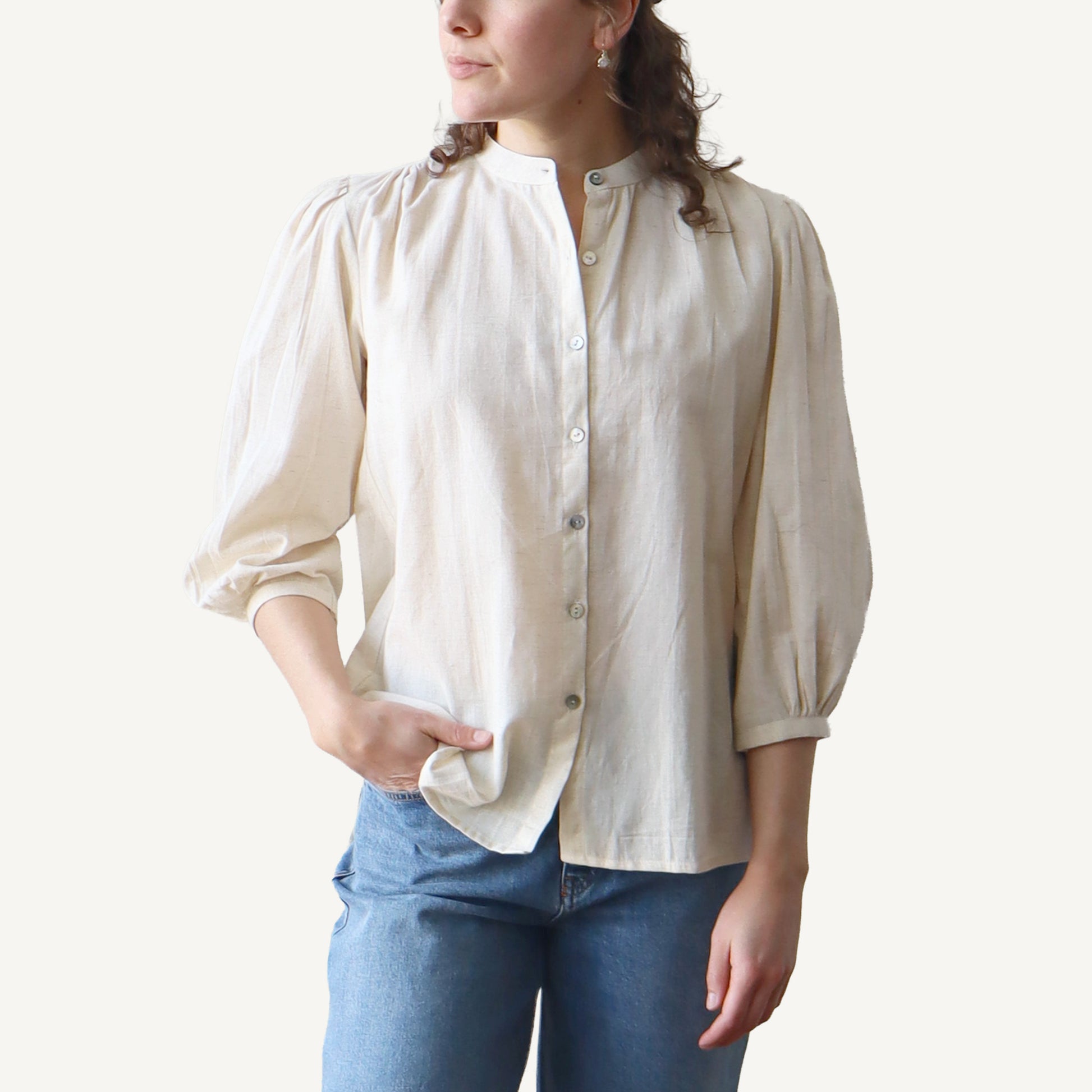 Woman wearing a beige blouse and blue jeans on a white background