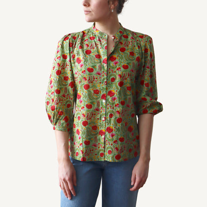 Woman wearing a green floral blouse with red flowers on a white background