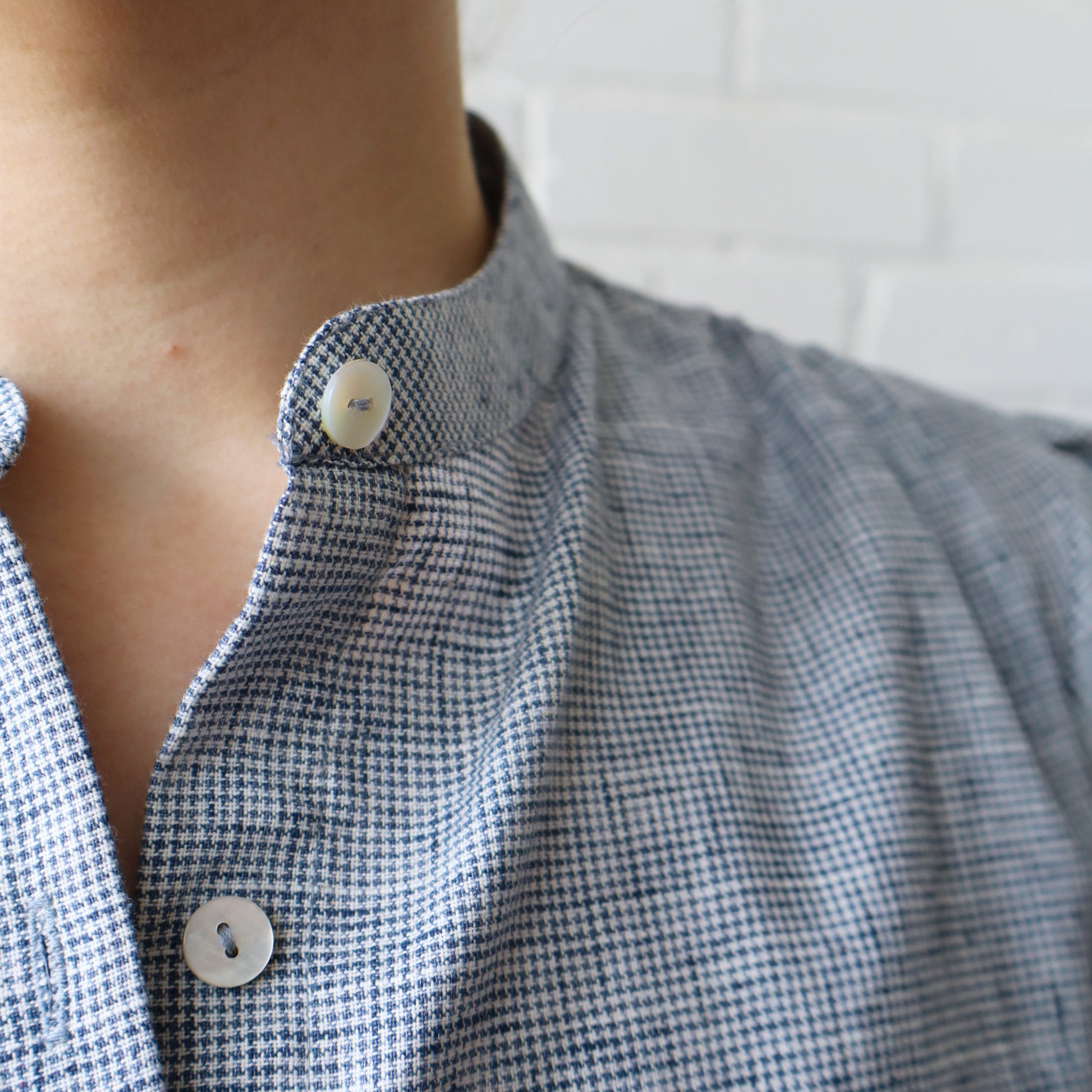 Close-up of a person wearing a blue checkered shirt with buttons.
