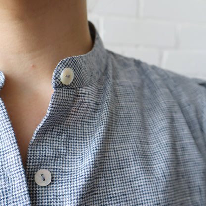 Close-up of a person wearing a blue checkered shirt with buttons.