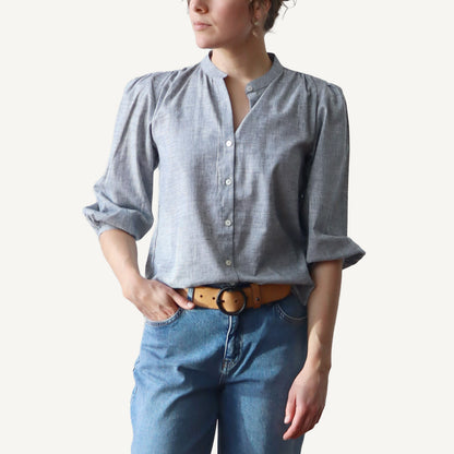 Person wearing a light blue button-up shirt and jeans on a plain background