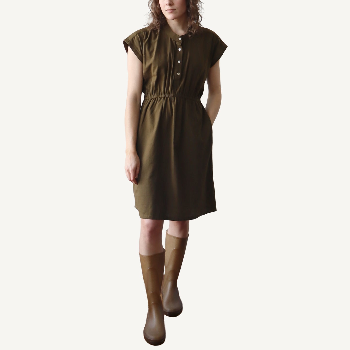 Woman wearing a brown dress and boots on a white background