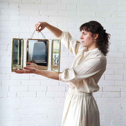 Woman holding a decorative mirror against a white brick wall