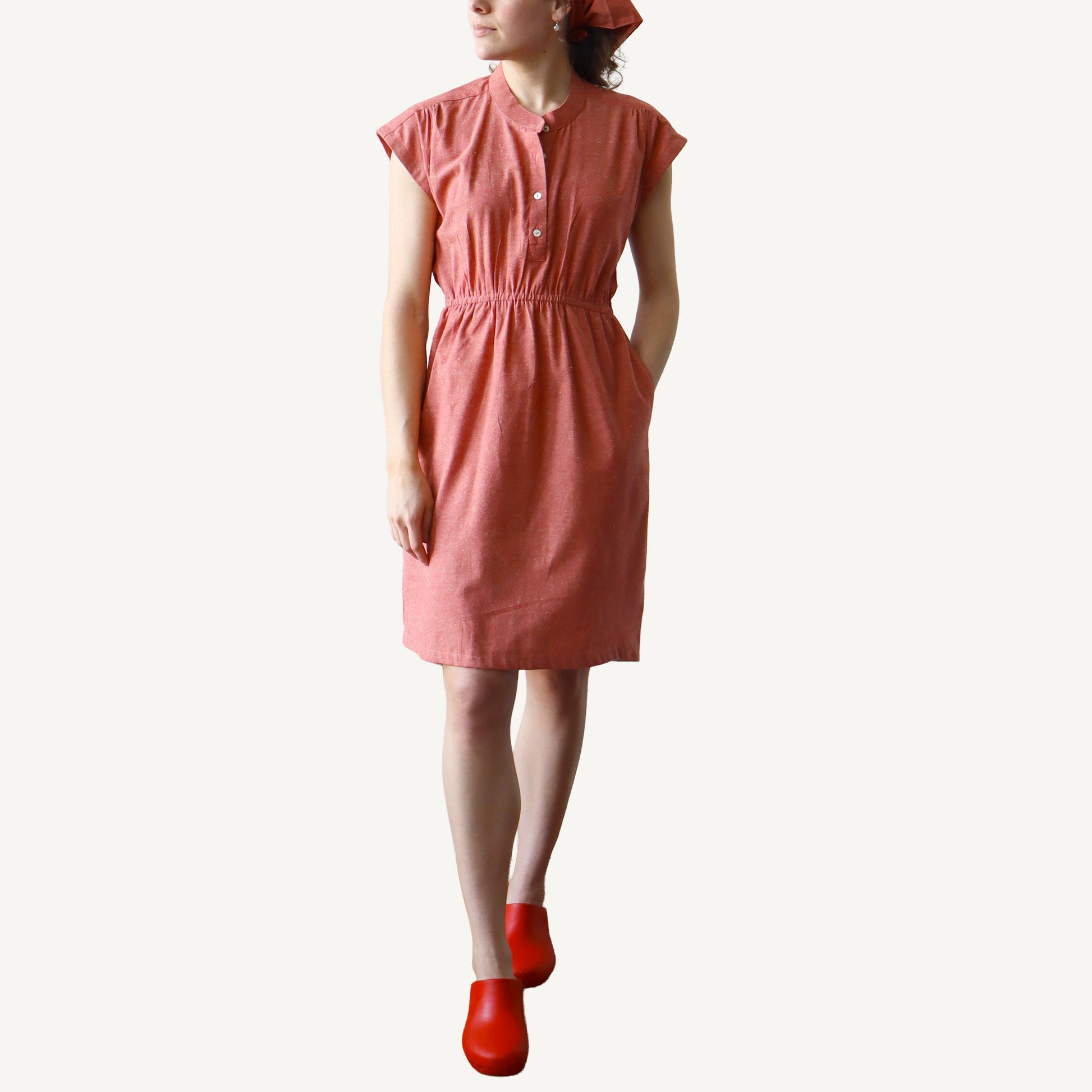 Woman wearing a pink dress with red shoes on a white background