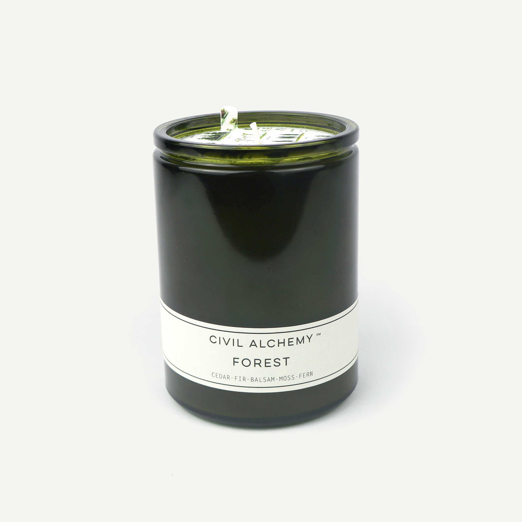 Candle in a green container with a white label on a white background