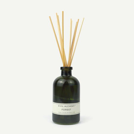 Reed diffuser with wooden sticks in a dark green bottle on a white background