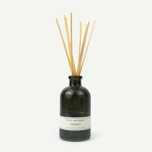 Reed diffuser with wooden sticks in a dark green bottle on a white background
