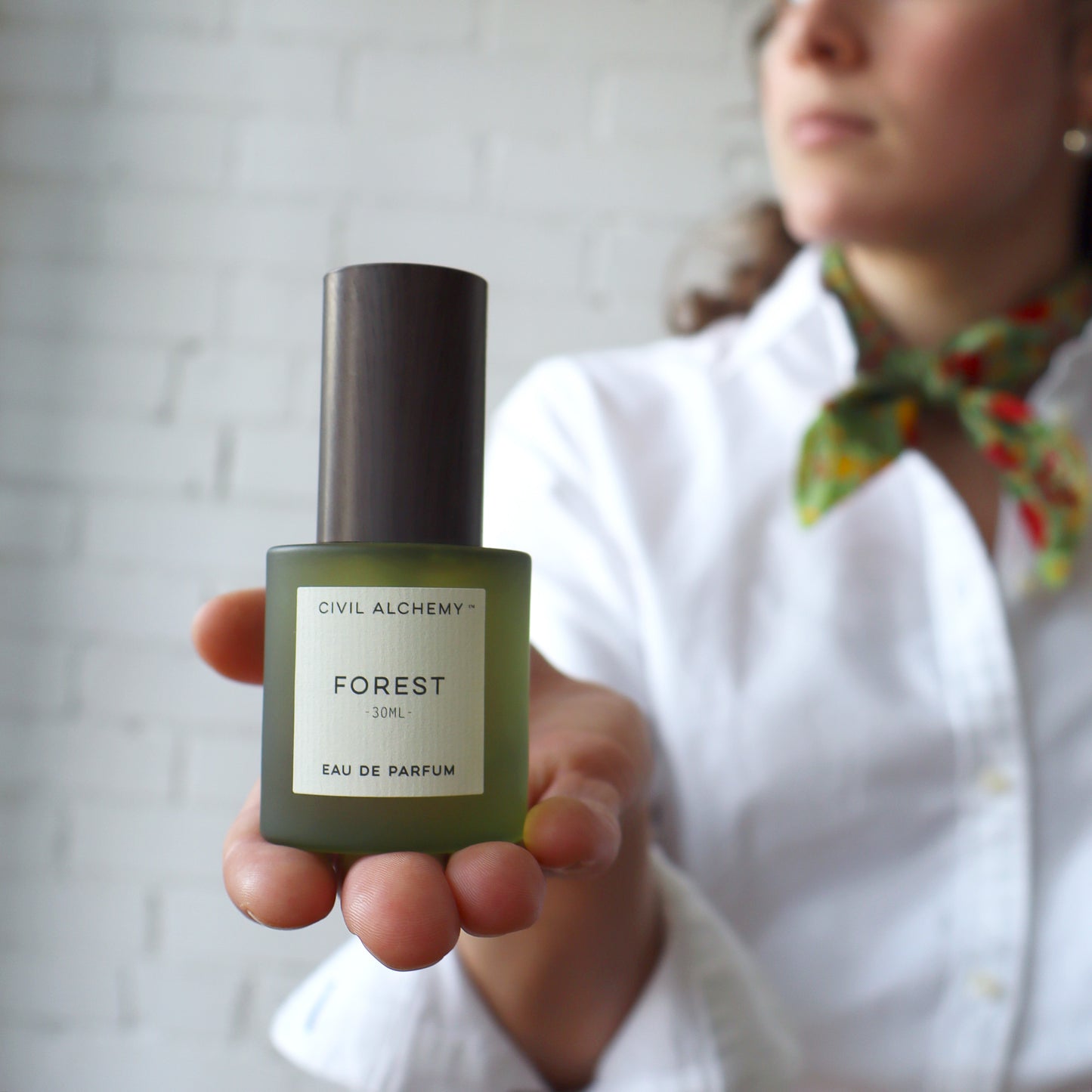 Person holding a bottle of 'Forest' perfume by Civil Alchemy against a neutral background