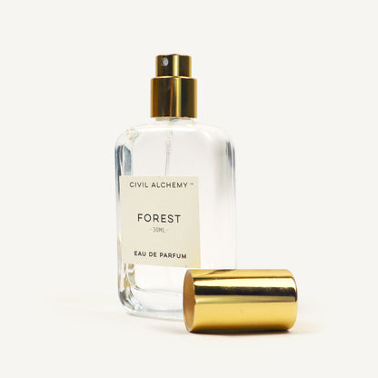 Clear perfume bottle with gold cap labeled 'Forest' by Civil Alchemy on a white background