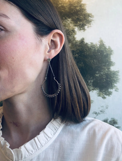 Close-up of a person wearing an earring with a blurred natural background