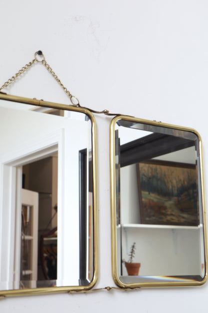 Brass-framed mirror with chain on a white wall