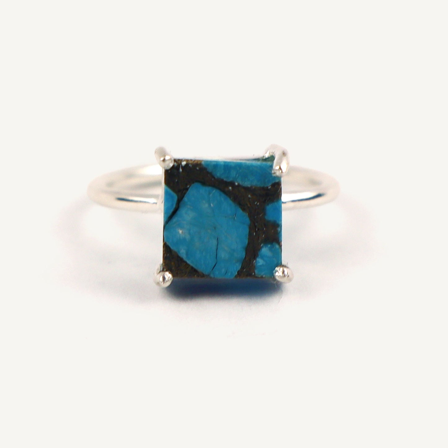 Silver ring with a square blue stone on a white background