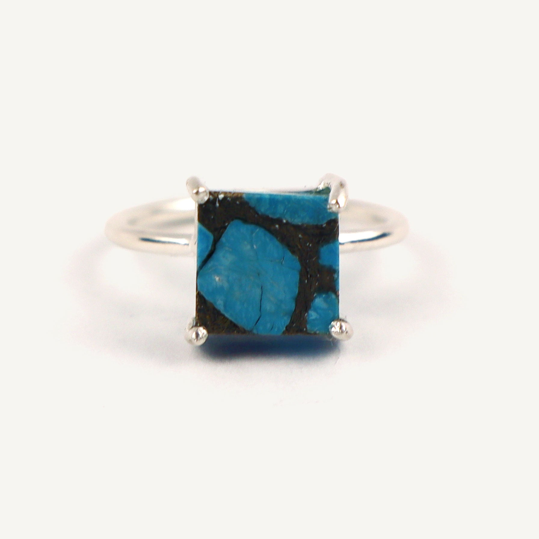 Silver ring with a square blue stone on a white background