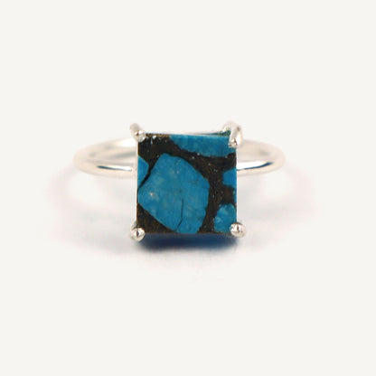 Silver ring with a square blue stone on a white background
