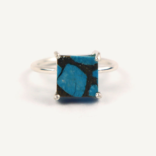 Silver ring with a square blue stone on a white background