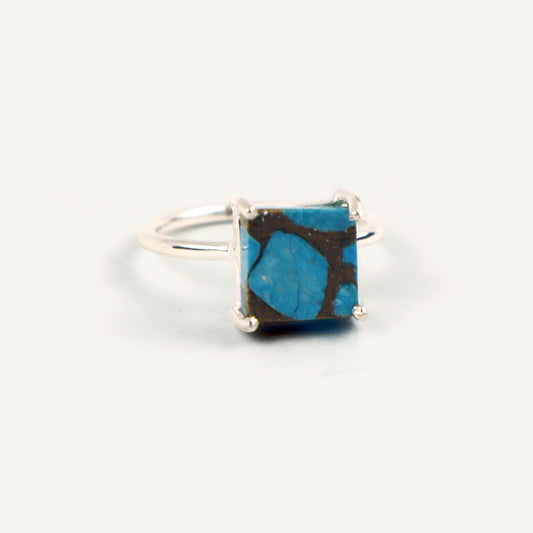 Silver ring with a square blue stone on a white background