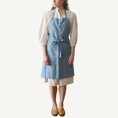 Person wearing a blue apron over a white shirt on a white background