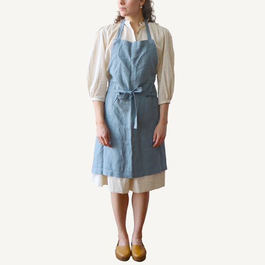 Person wearing a blue apron over a white shirt on a white background