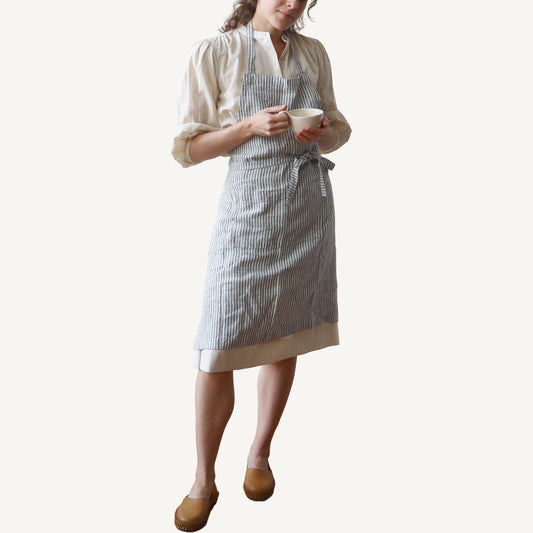 Person wearing a striped apron holding a cup on a white background
