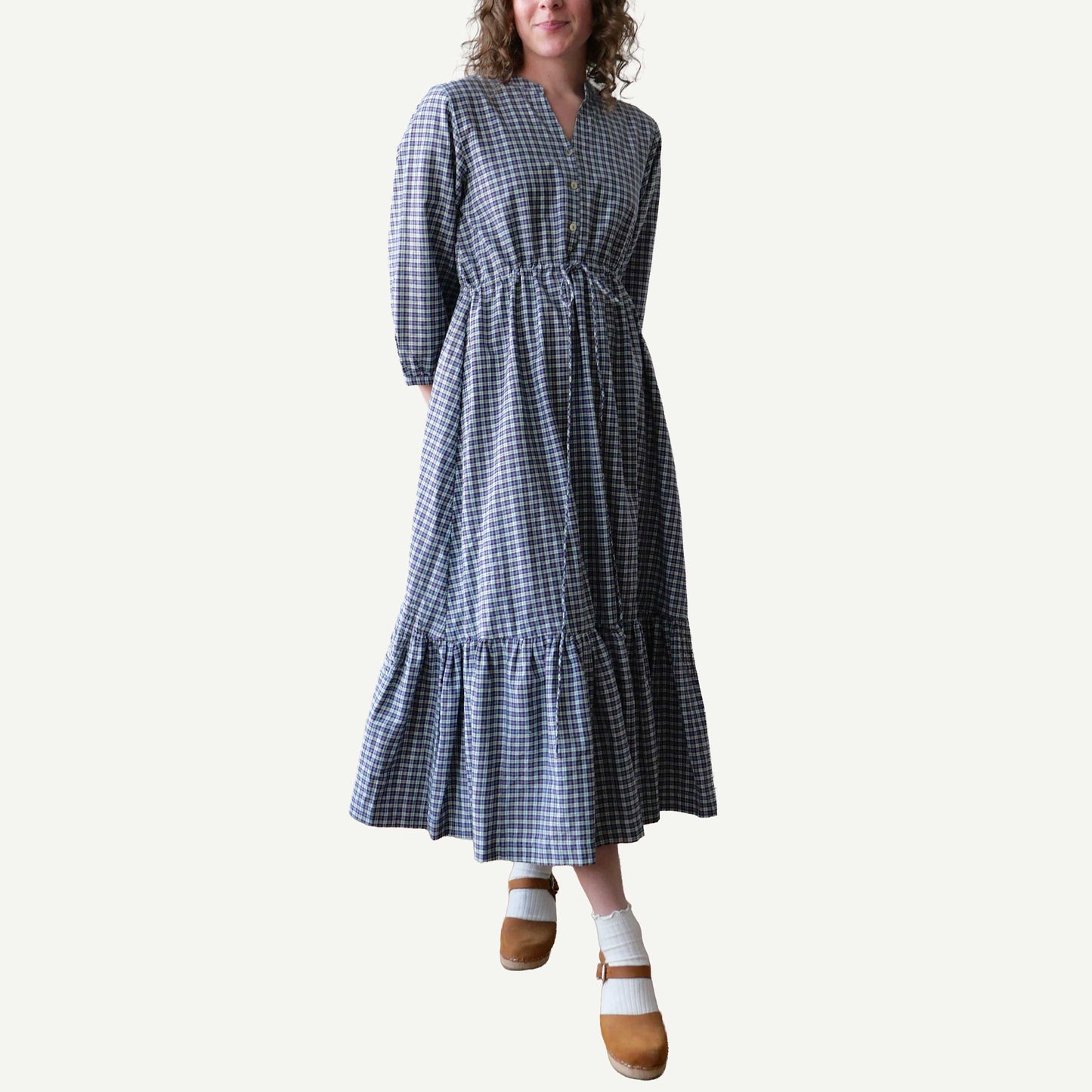 Woman wearing a blue and white checkered dress on a plain background