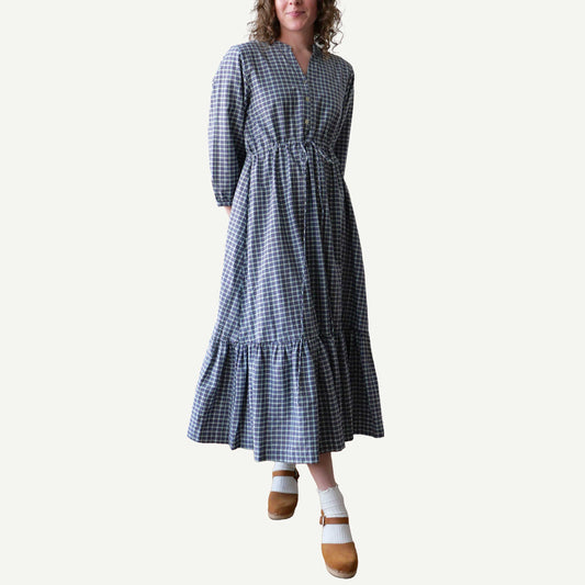 Woman wearing a blue and white checkered dress on a plain background