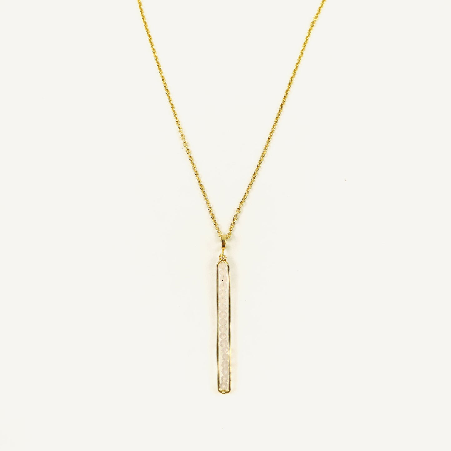 Gold necklace with a vertical bar pendant on a white background