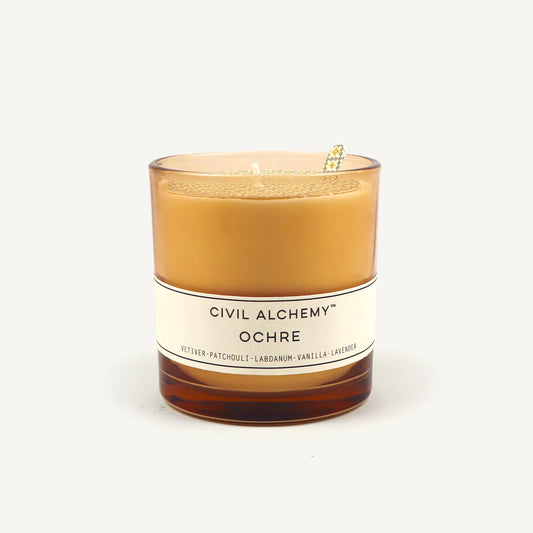 Candle with 'Civil Alchemy Ochre' label on a white background