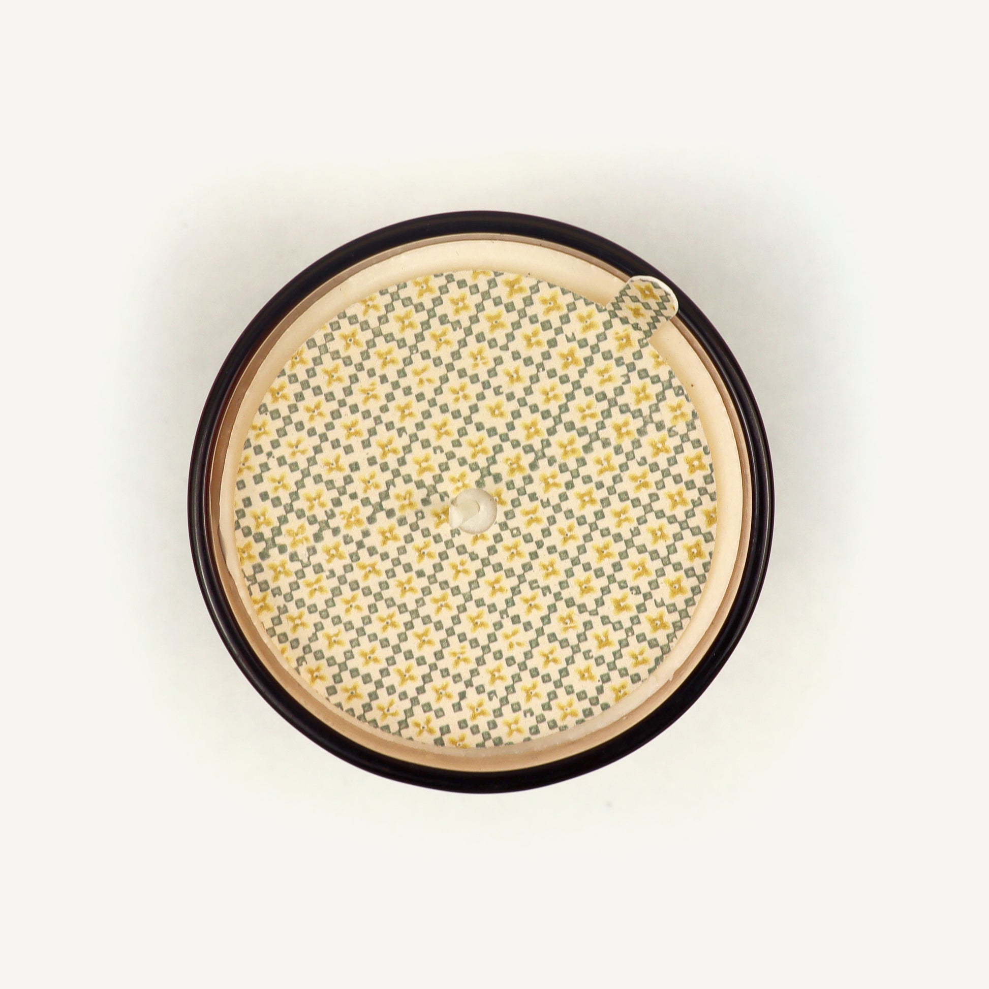 Round candle topper with floral pattern on a beige background