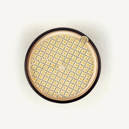 Round candle topper with floral pattern on a beige background