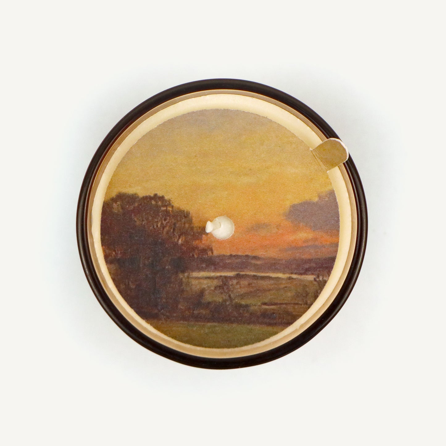 Round candle topper with a sunset design on a white background