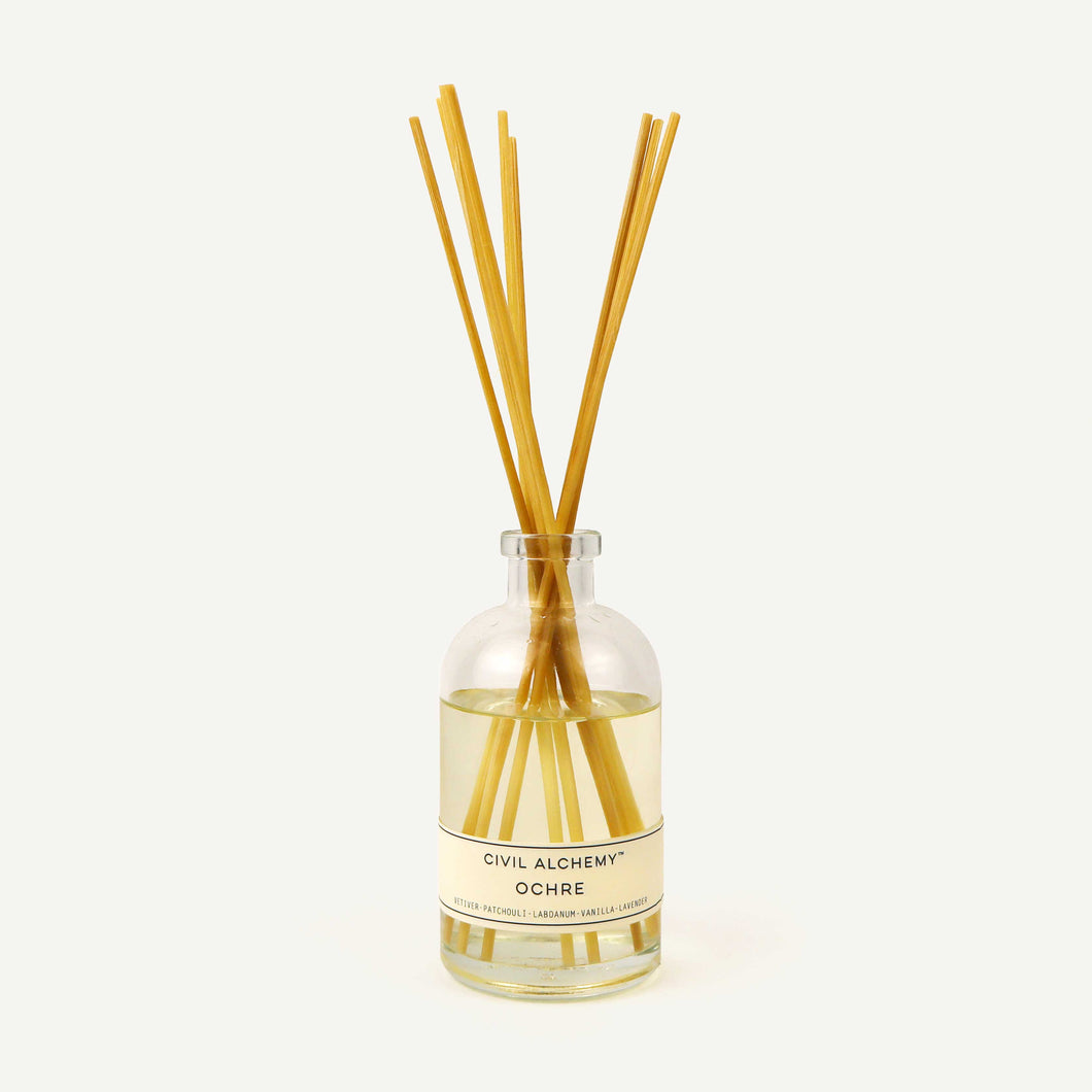 Diffuser with wooden sticks and 'Civil Alchemy Ochre' label on a white background