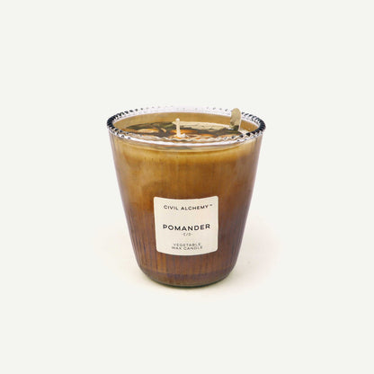 Candle in a glass jar with a label "Pomander" on a white background