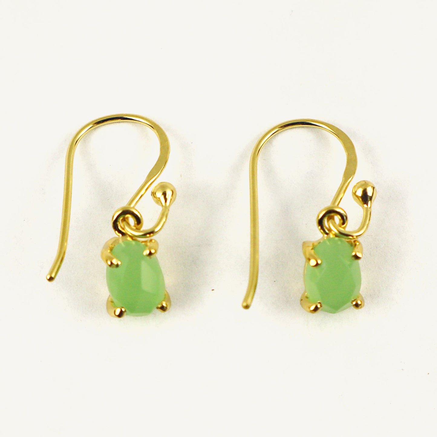 Gold earrings with green gemstones on a white background