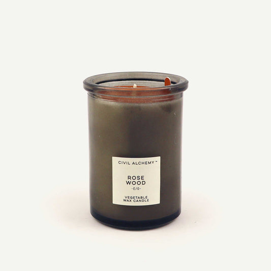 Candle in a glass jar labeled 'Rose Wood' by Civil Alchemy on a white background