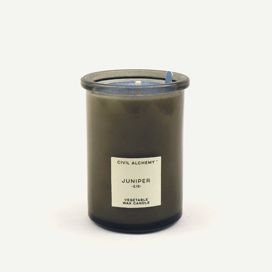 Candle in a glass jar labeled 'Juniper' by Civil Alchemy on a white background
