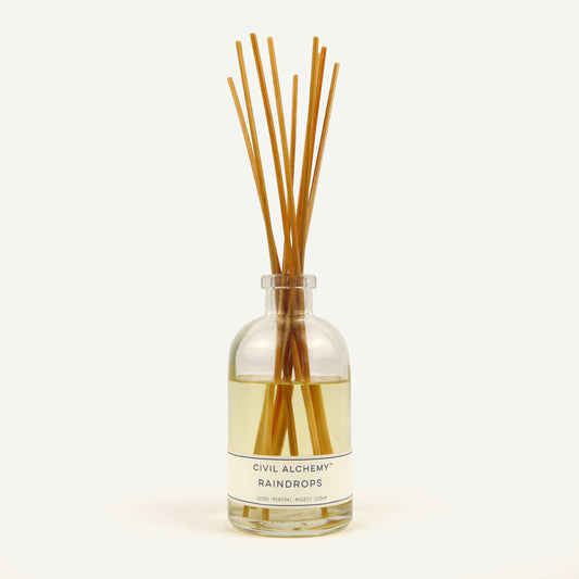 Diffuser bottle with wooden sticks labeled 'Raindrops' by 'Civil Alchemy' on a light background