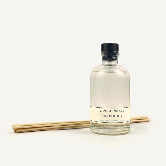 Bottle of 'Raindrops' by Civil Alchemy with reeds on a white background