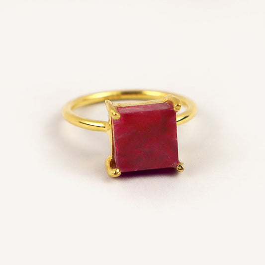 Gold ring with a red gemstone on a white background