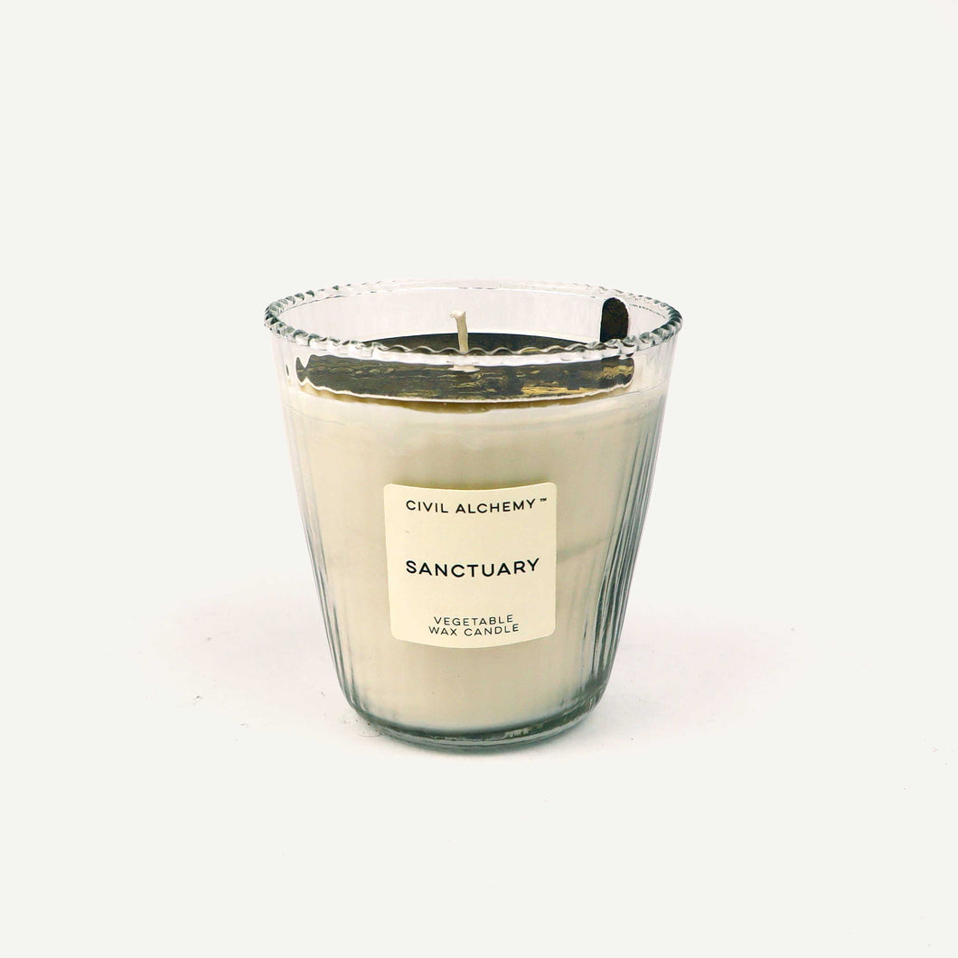 Candle in a glass jar labeled 'Sanctuary' by Civil Alchemy on a white background