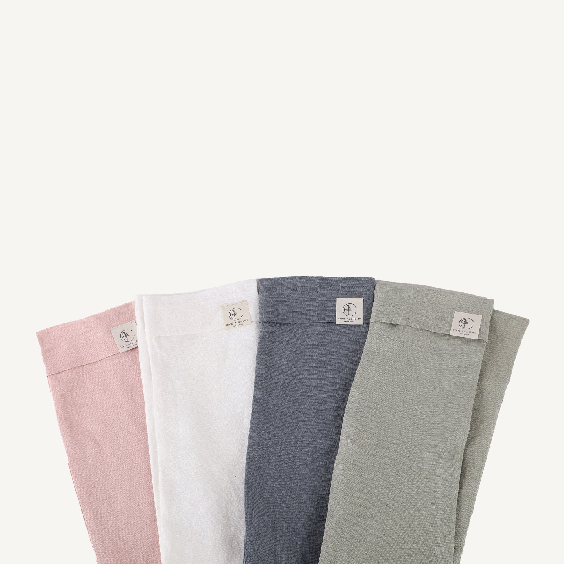 Four pairs of folded pants in pink, white, blue, and sage on a white background.