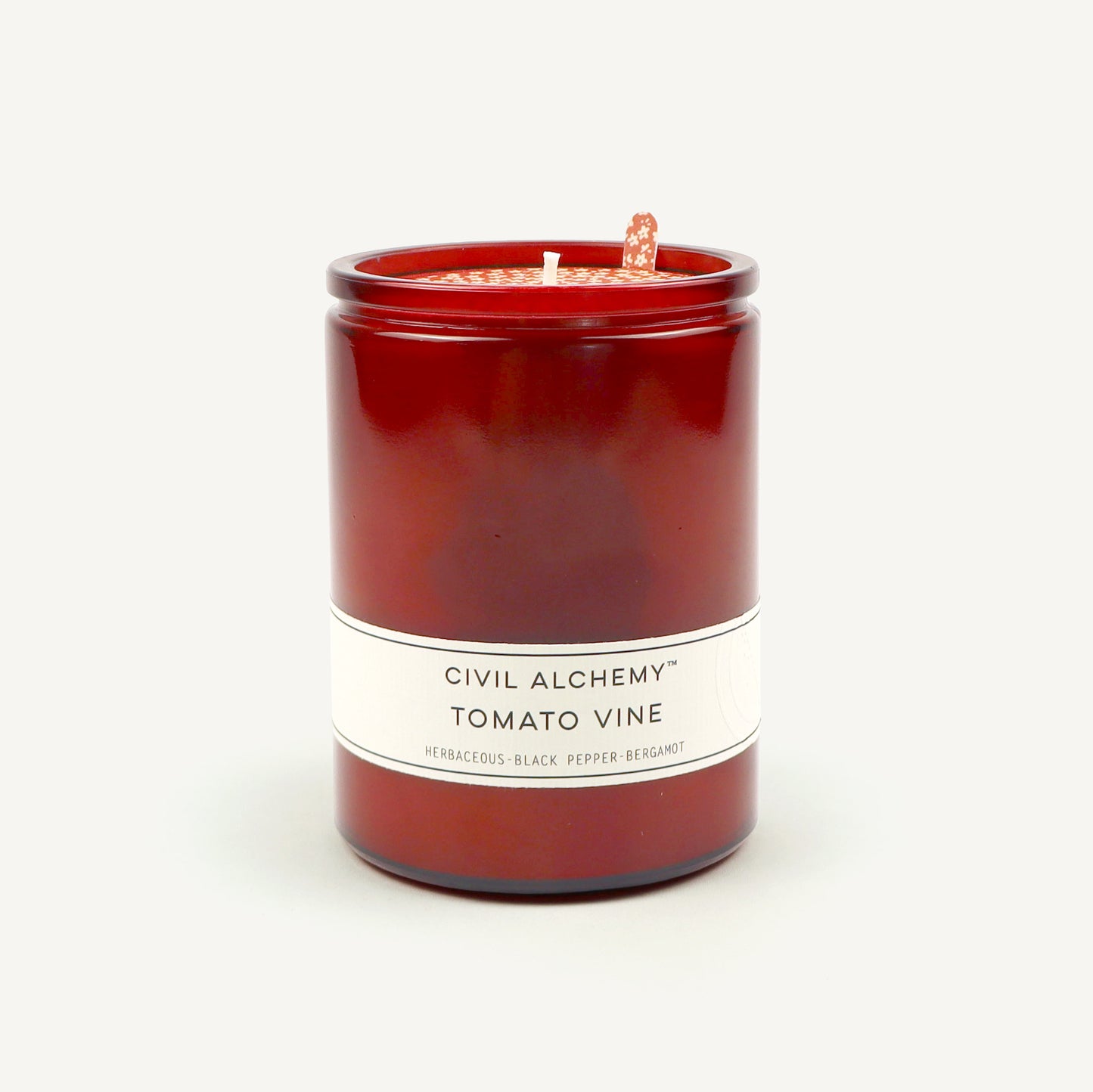 Red candle with a white label on a light gray background