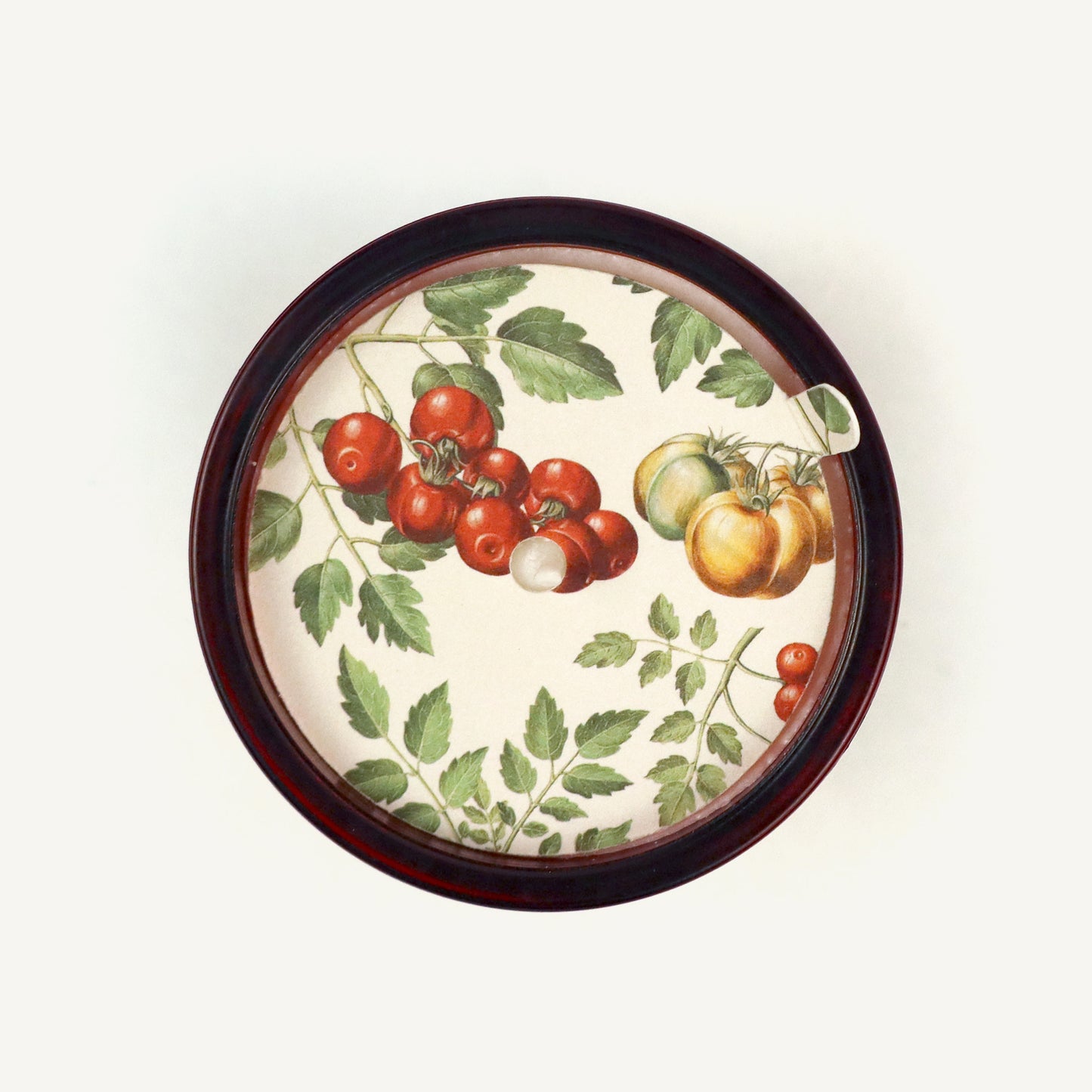 Decorative candle topper with tomato and leaf design on a white background
